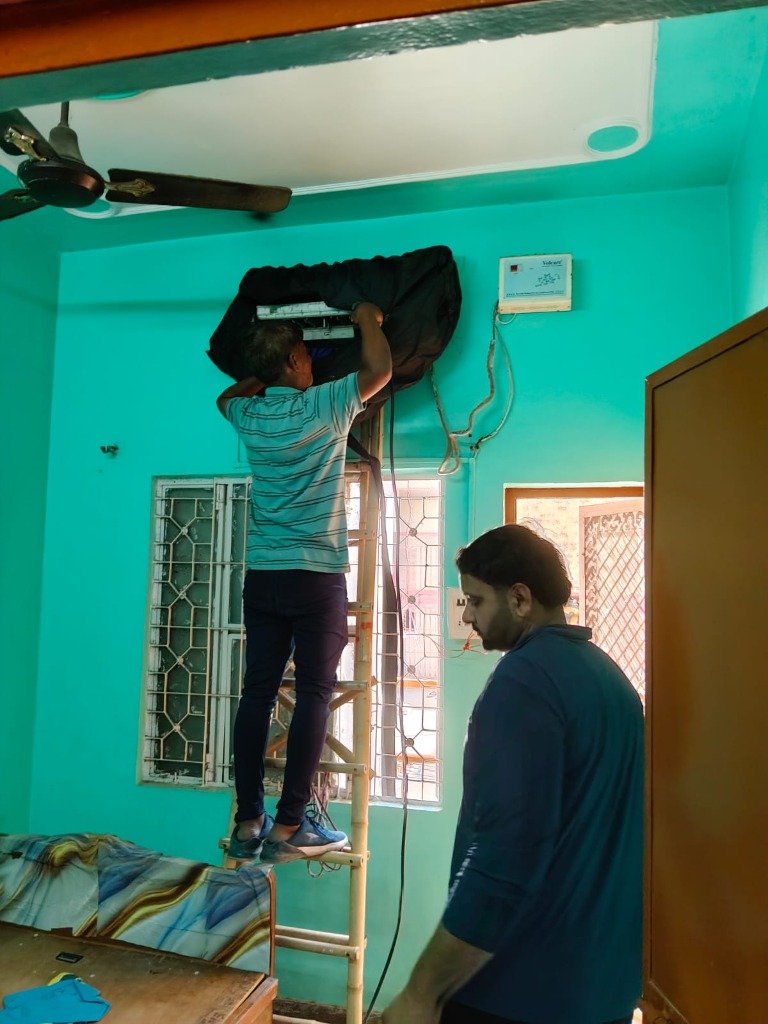 Technician on ladder deep cleaning high wall AC unit