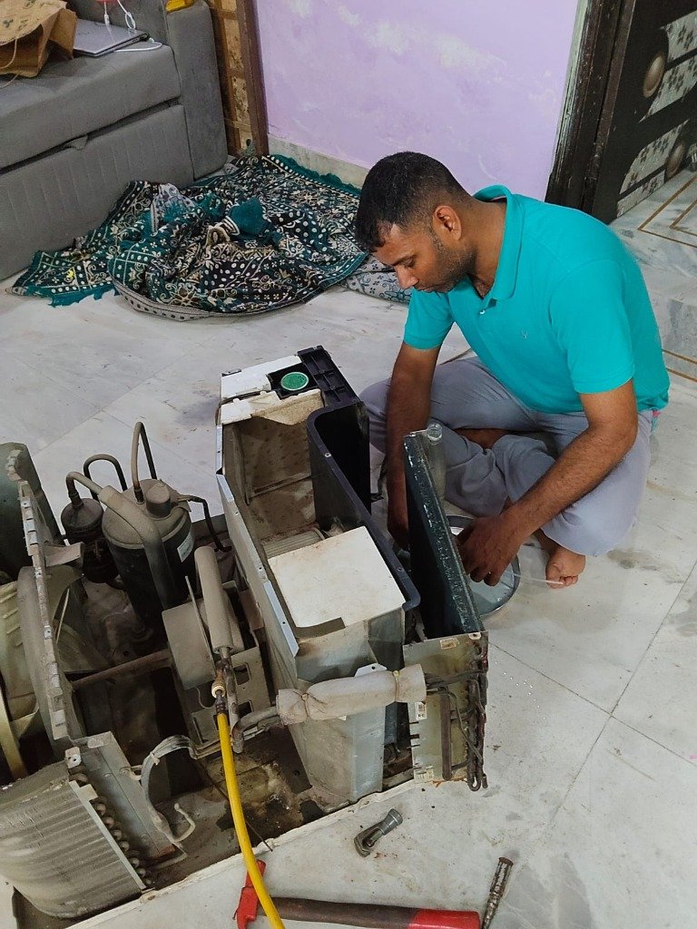 Technician servicing outdoor AC compressor on site